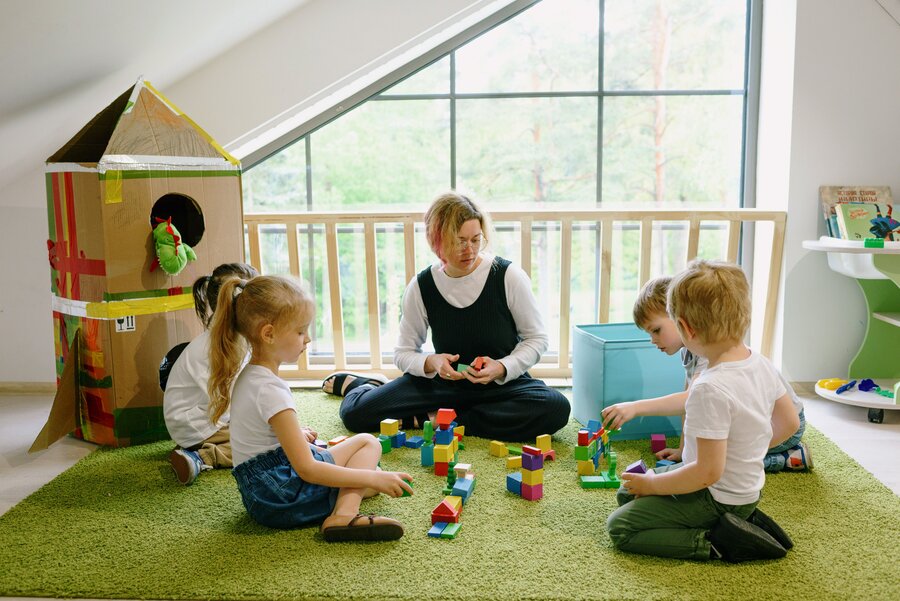 An educator and two children playing together with colourful blocks